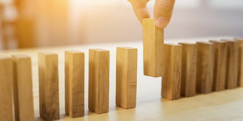 Person picking up wooden brick from a line