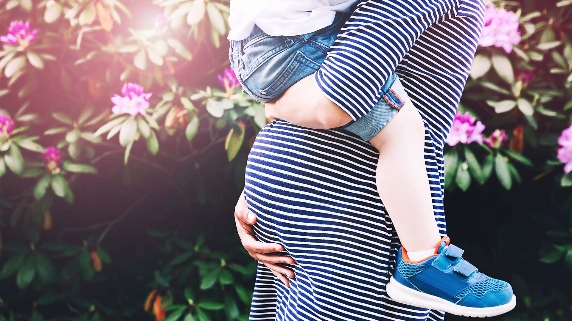 Photo of pregnant mother cradling bump whilst carrying child
