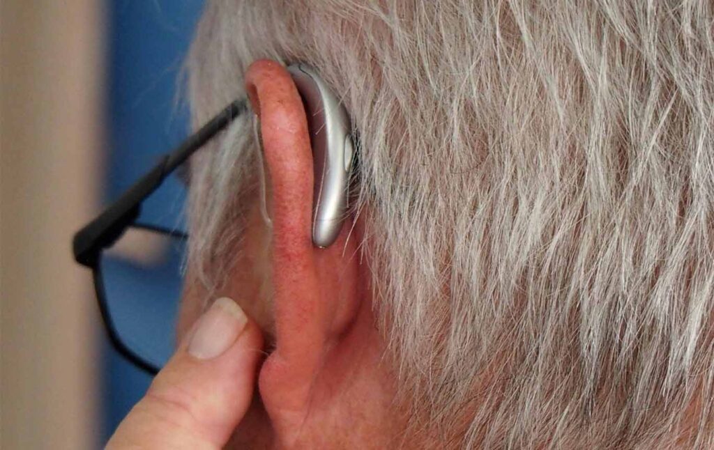 Elderly man touching hearing aid